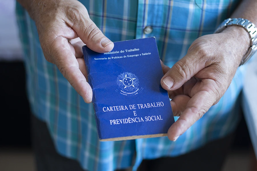 mãos do trabalhador segurando carteira de trabalho
